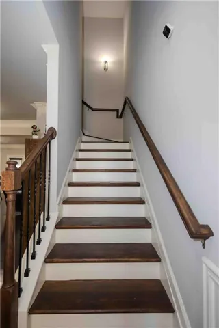 Staircase featuring wood-finish treads, white risers, and a wood-finish handrail