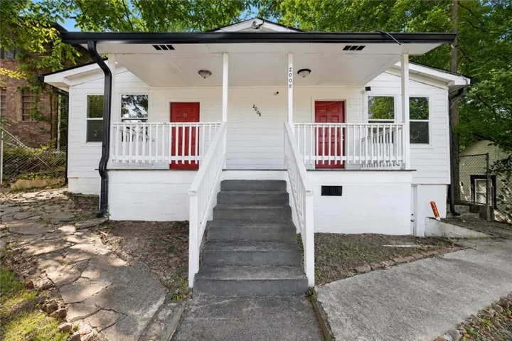 White exterior with red entry doors, a covered porch, and white porch railings