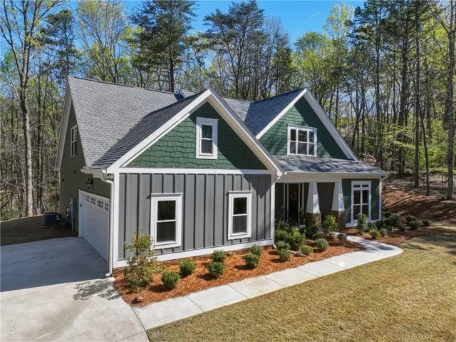 Modern farmhouse exterior featuring board and batten siding, shake siding, an attached garage, a concrete driveway, and a front walkway
