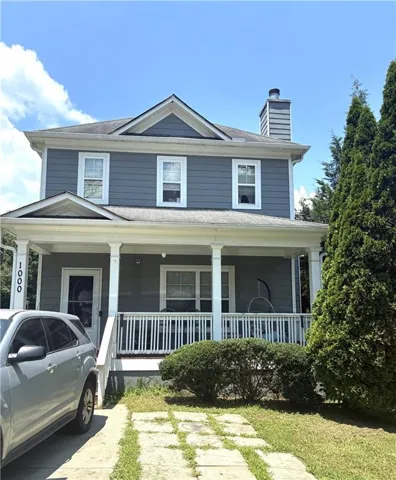 Two-story residence with gray siding, multiple gables, and a prominent front porch