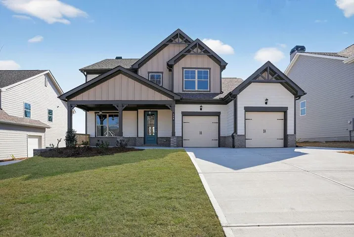 Craftsman-style home featuring board and batten siding, covered porch, driveway, a garage, and a front yard