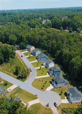Cul-de-sac street with newly constructed residences, each featuring a pitched roof and a paved driveway