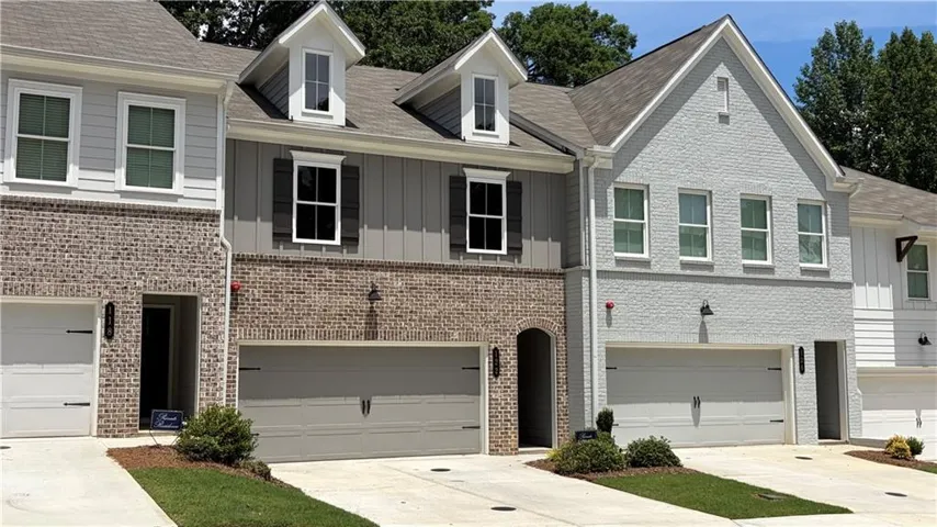 Townhome exterior featuring brick and siding accents, dormer windows, and attached garages