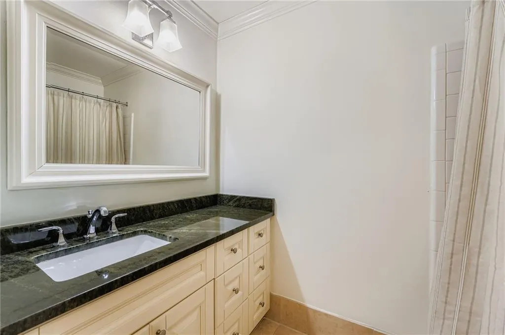 Full bath with vanity, curtained shower, ornamental molding, and light tile patterned flooring Full bath with vanity, curtained shower, ornamental molding, and light tile patterned flooring