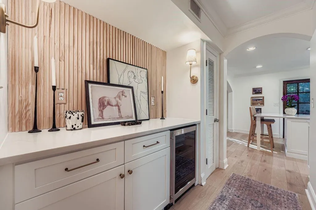 Bar featuring arched walkways, beverage cooler, Shaker cabinets, light hardwood flooring, and crown molding Bar featuring arched walkways, beverage cooler, Shaker cabinets, light hardwood flooring, and crown molding