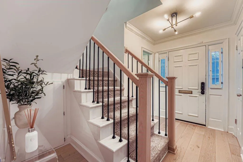 Entrance foyer featuring light hardwood floors, ornamental molding, and stairway Entrance foyer featuring light hardwood floors, ornamental molding, and stairway