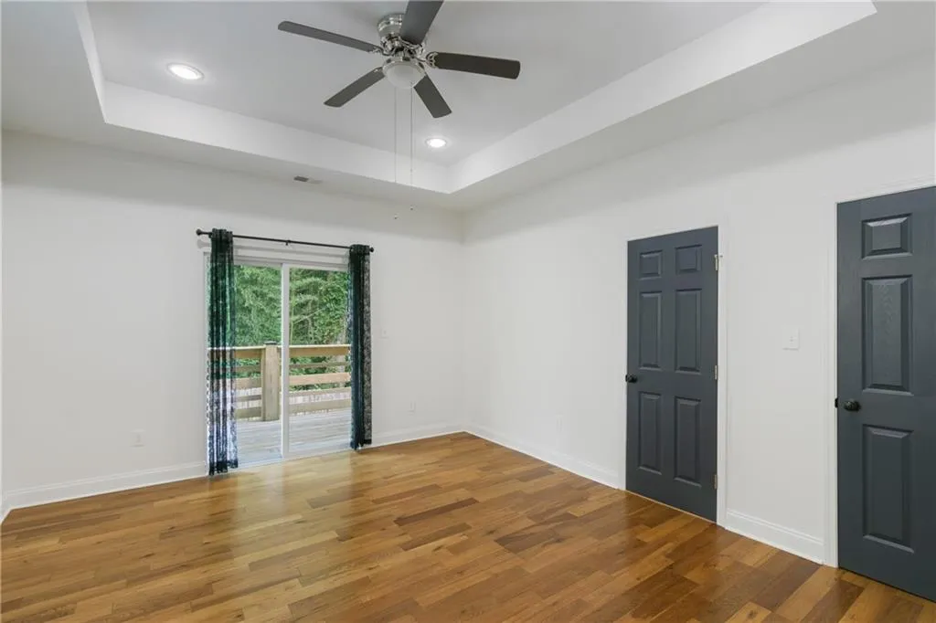 Empty room featuring a raised ceiling, recessed lighting, wood finished floors, and ceiling fan
