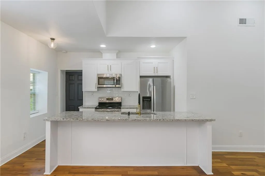 Kitchen with white cabinetry, light stone countertops, decorative backsplash, stainless steel appliances, and recessed lighting