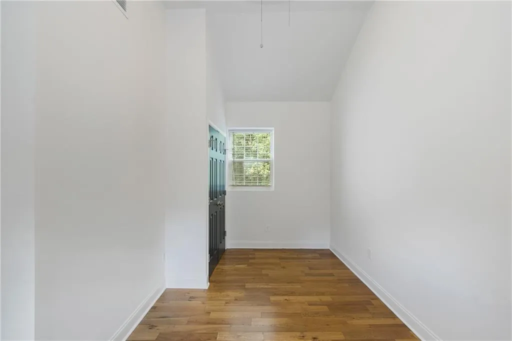 Spare room with dark wood-style flooring and vaulted ceiling