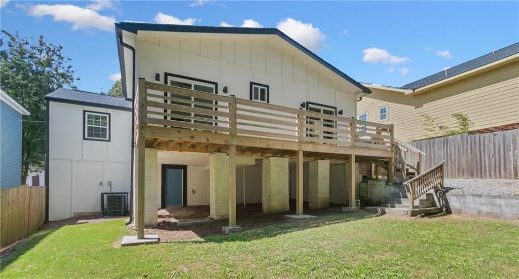 Back of house with board and batten siding, a wooden deck, stairs, and oil tank
