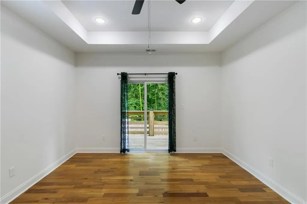 Spare room featuring wood finished floors, a raised ceiling, a ceiling fan, and recessed lighting