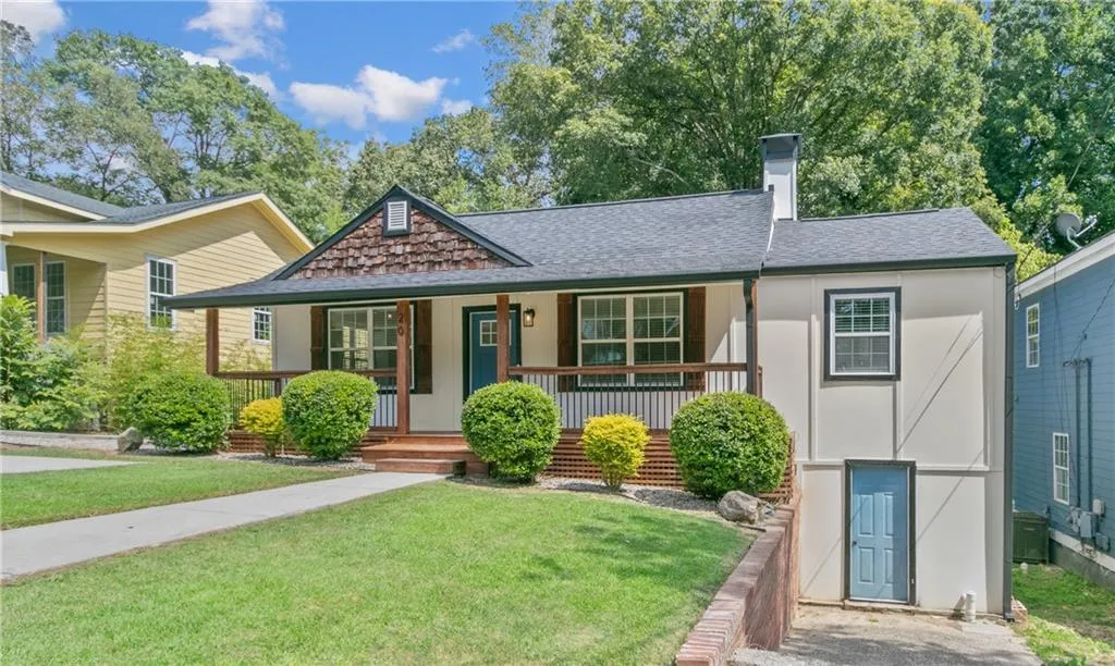 View of front of property with roof with shingles, a chimney, a porch, and a front yard