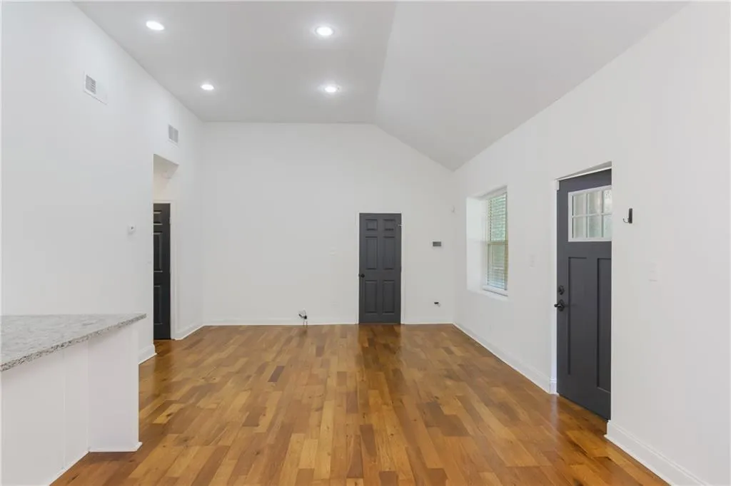Spare room featuring vaulted ceiling, wood finished floors, and recessed lighting