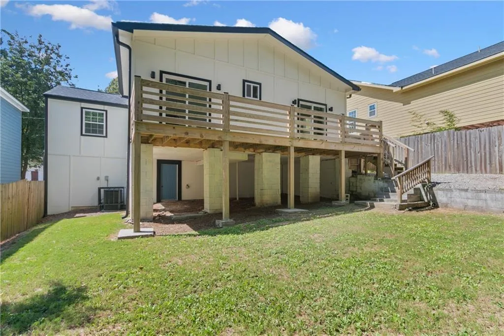 Rear view of property featuring a wooden deck, board and batten siding, stairs, and oil tank