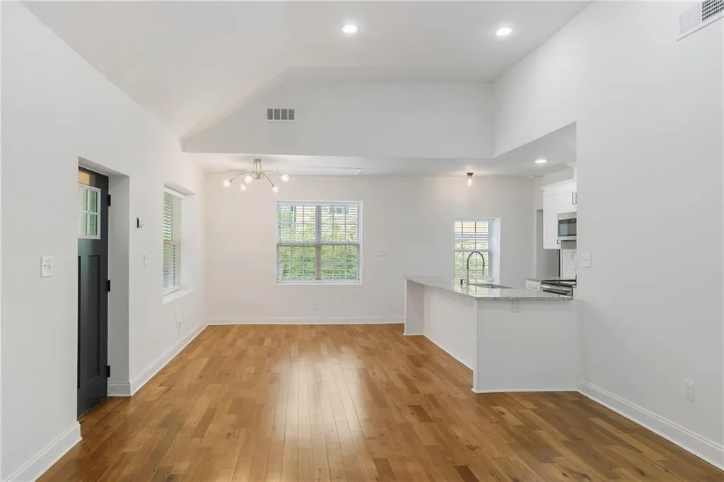 Unfurnished living room with recessed lighting, light wood-style flooring, vaulted ceiling, and a chandelier