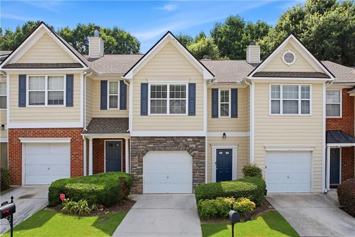 Townhome exterior with light-colored siding, dark blue shutters, a dark blue entry door, and a single-car garage