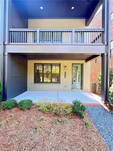 Brick exterior with an upper-level balcony, ground-level patio, and landscaped planting beds