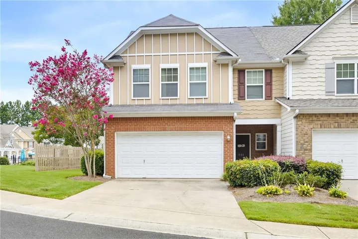 Townhome exterior featuring a two-car garage, brick facade, and decorative shutters