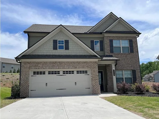 Two-story residence featuring a brick and siding exterior, multi-gabled roofline, attached garage, and a concrete driveway