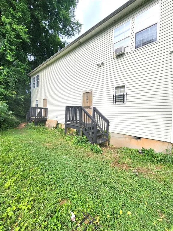 Back of property with crawl space, a lawn, and cooling unit