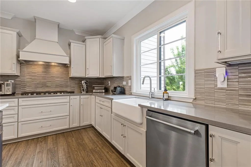 Kitchen featuring stainless steel appliances, white cabinetry, dark wood-style floors, and dark stone counters
