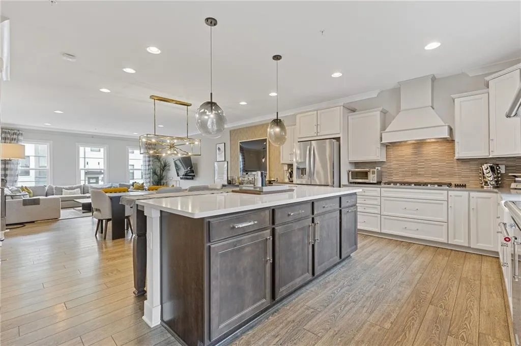 Dual tone kitchen featuring crown molding, dual tone cabinets, open floor plan, a kitchen island, and stainless steel refrigerator with ice dispenser