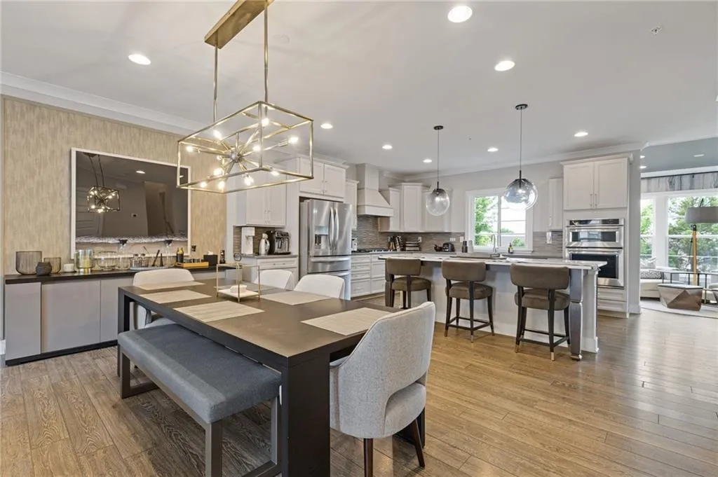 Dining area with light wood finished floors, crown molding, and suspended lighting