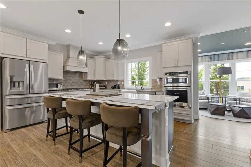 Kitchen featuring stainless steel appliances, a kitchen bar, dark wood finished floors, decorative backsplash, and pendant lighting