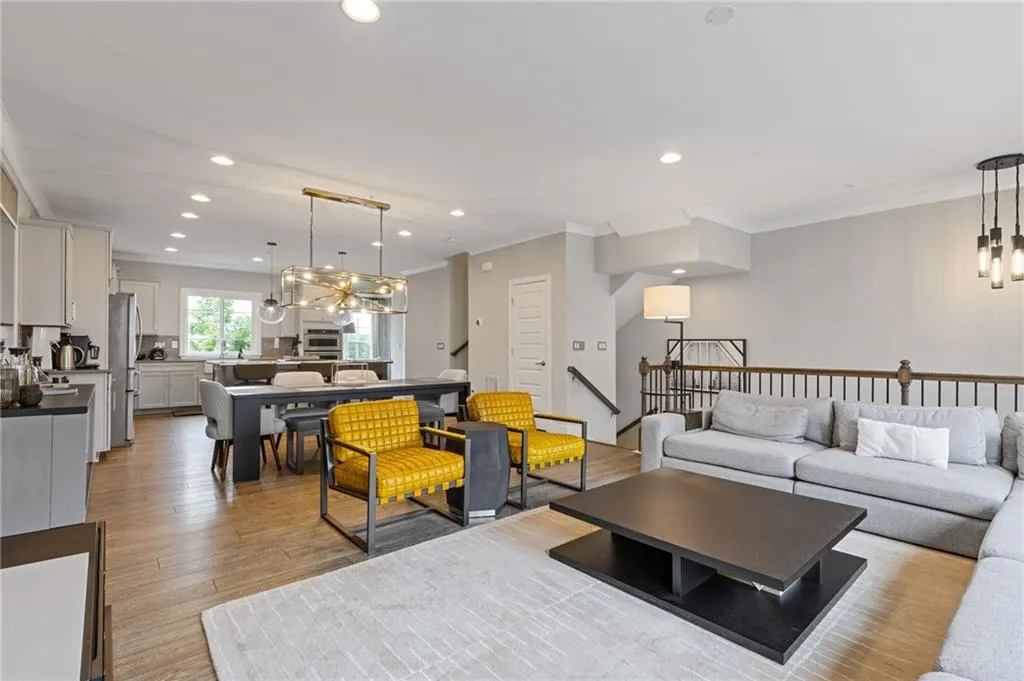 Living area with hanging lights, ornamental molding, and light wood-style flooring