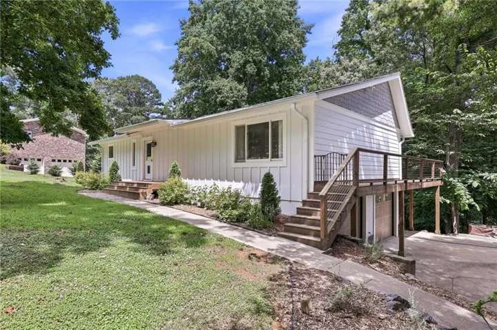 White vertical siding exterior with shingle accents and a multi-level wood deck