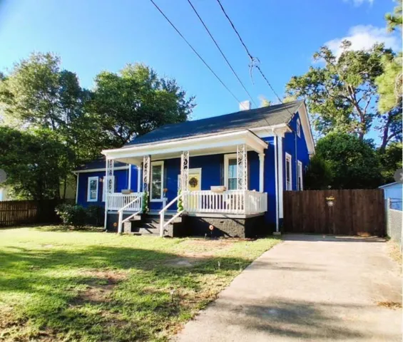 Charming cottage-style home featuring a striking cobalt blue exterior with crisp white trim and wraparound porch