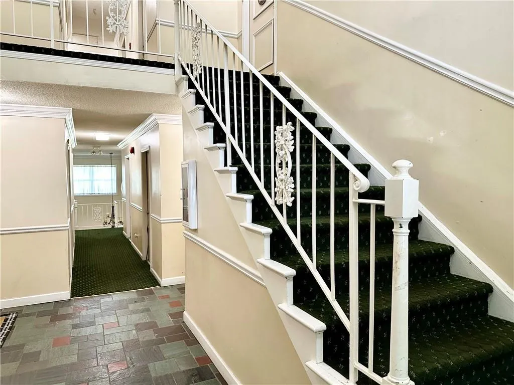 Stairway featuring dark tile flooring and crown molding