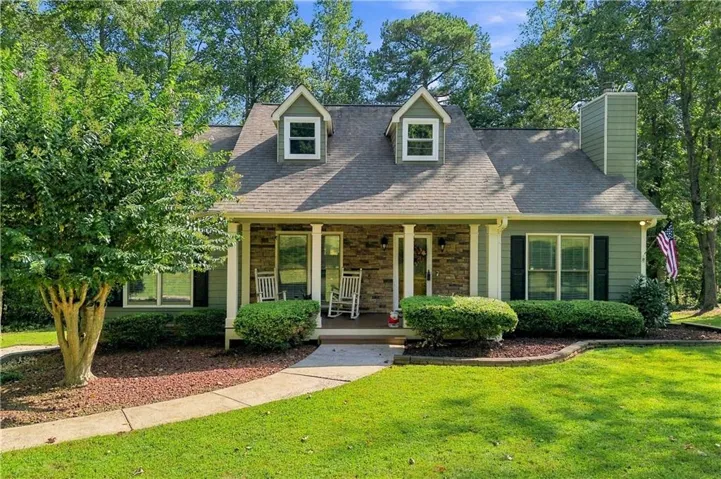 Siding exterior with stone accents, covered front porch, prominent dormer windows, and a chimney feature