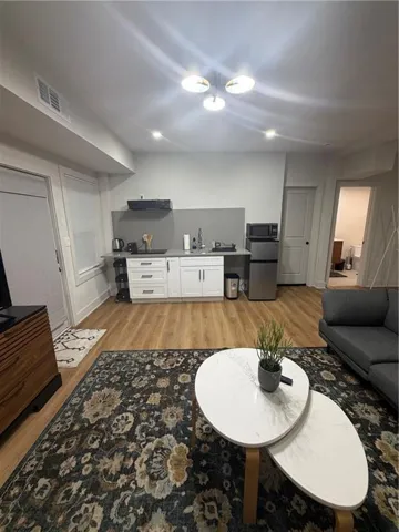Light wood-finish flooring, white cabinetry, stainless steel appliances, and recessed lighting