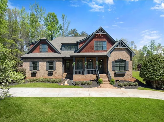 Craftsman-style house with a front lawn, a porch, and brick siding