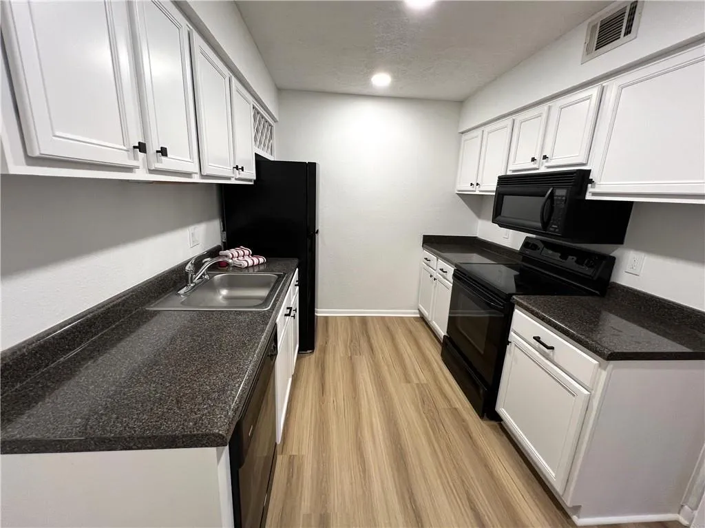 Kitchen featuring black appliances, white cabinets, new hardware, and new flooring
