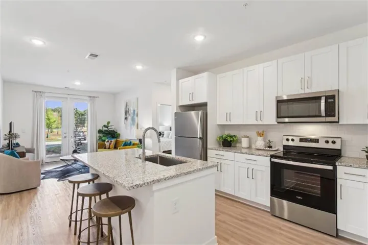 Kitchen with stainless steel appliances, open floor plan, white cabinets, light wood finished floors, and recessed lighting