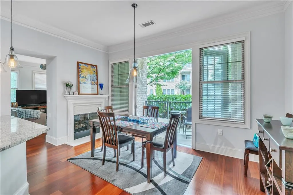 Dining room featuring crown molding and dark hardwood / wood-style floors, fireplace, and access to patio