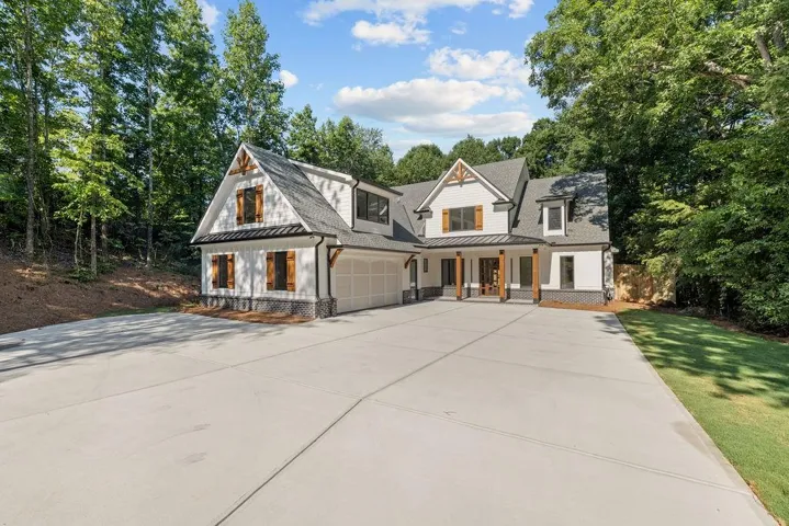 Modern inspired farmhouse with an attached garage, a shingled roof, a standing seam roof, covered porch, and driveway