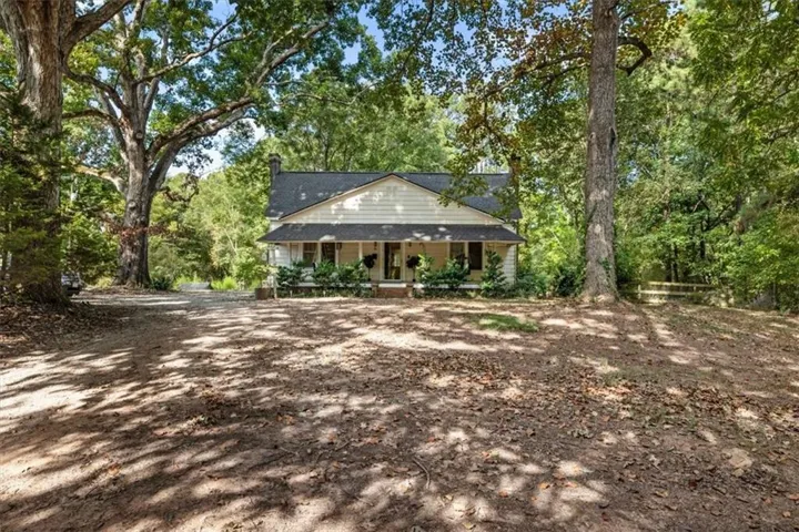 Ranch-style residence featuring a covered front porch, a gabled roofline, and a chimney