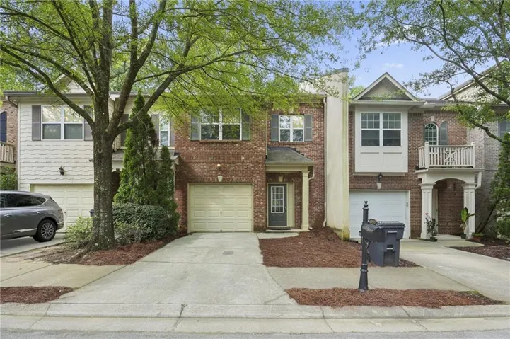 Brick exterior with architectural columns, multiple garage spaces, and a covered front entry