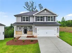 Two-story residence featuring grey siding, dark shutters, an attached two-car garage, and a covered front porch