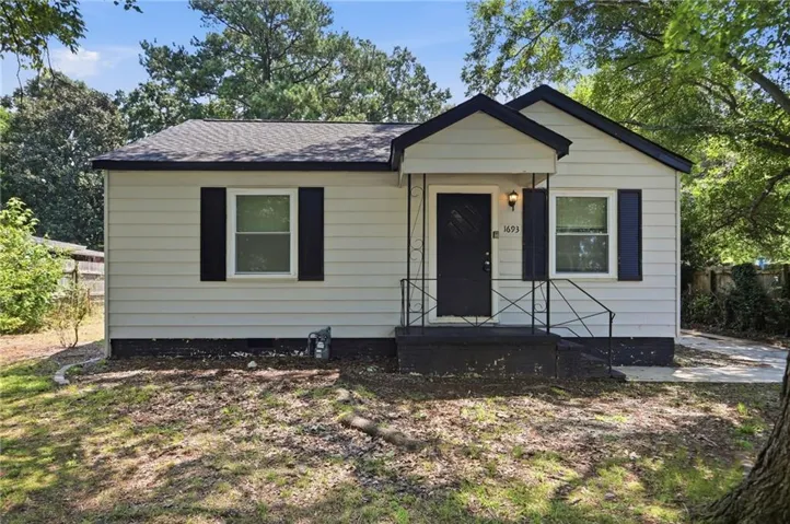Siding exterior with contrasting dark shutters, covered entry, and black wrought iron railings