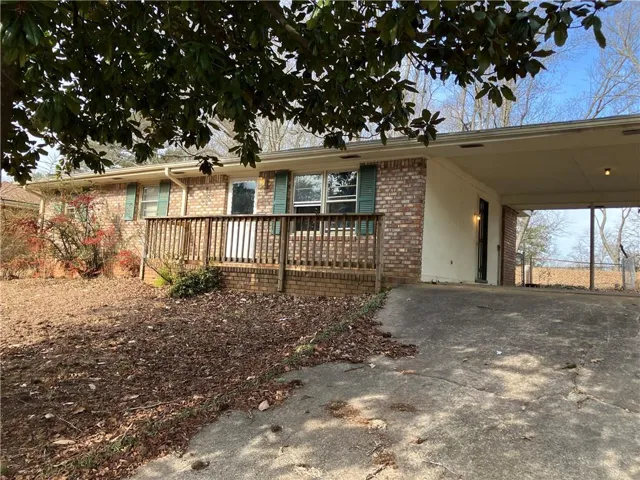 Brick exterior with green shutters, a wood deck, and a connected carport