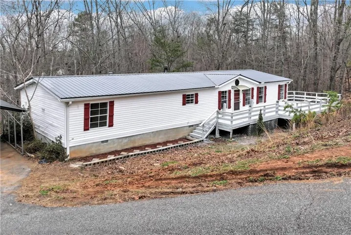 Manufactured / mobile home with crawl space, a metal roof, a carport, and driveway