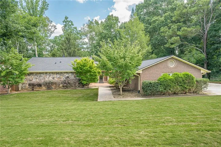 Expansive green lawn with a concrete walkway leading to the home