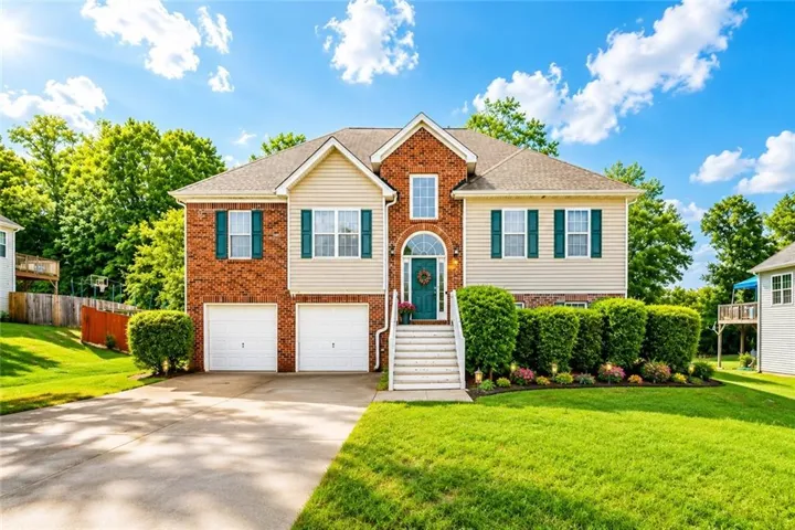 Two-story residence featuring brick and siding construction, a prominent arched entry, and two integrated garage doors