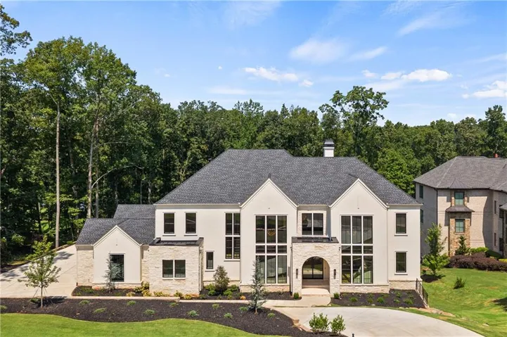 Contemporary stucco and stone-clad exterior with a dark shingle roof