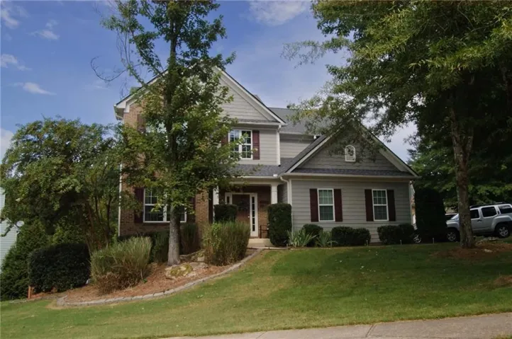 Two-story residence featuring a brick and siding exterior, a gabled roofline, and mature trees on the property