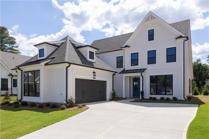 Modern farmhouse exterior featuring light-colored siding and a dark-toned roof